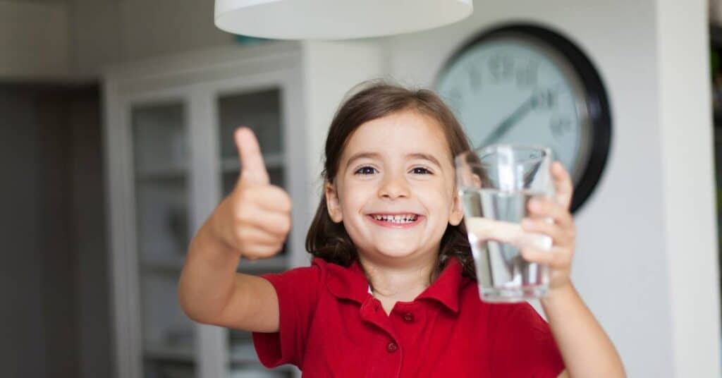 picie wody jako forma detoksu dziewczynka ze szklanką wody